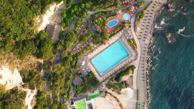 Pools and coastline of Ischia in summer season. Overhead aerial view from drone