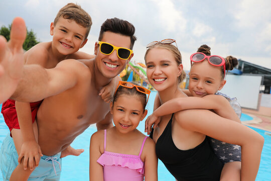 Happy family taking selfie near pool in water park