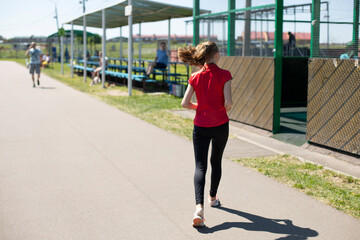 The girl is running down the street. Exercise. Urgent message.