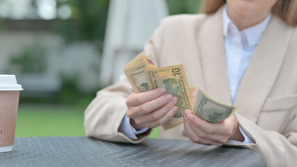 Close up of Businesswoman Counting Dollars in Outdoor Cafe 