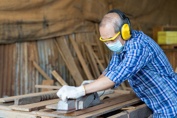 Asian male carpenter worker wearing  safety goggles and earmuffs at work. Asian senior male...