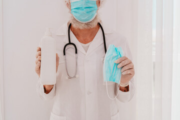 Fototapeta premium Doctor shows a disinfectant gel and a face mask for covid-19 virus