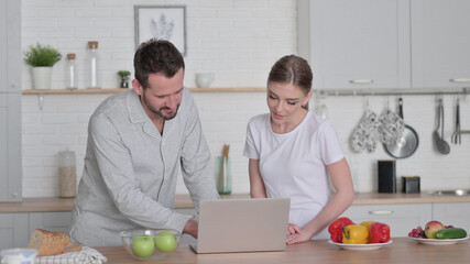 Woman and Man Working on Laptop in Kitchen