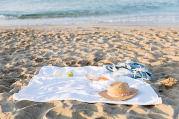 Summer picnic on the beach at sunset. Glasses, rose wine, hat, citrus fruits. Weekend picnic...