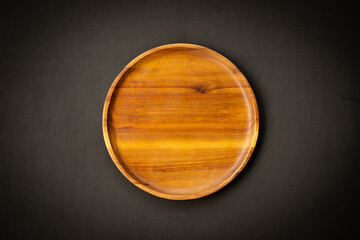 A wooden plate is placed on a black background.