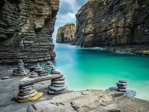 Cairns built alongside a turquoise bay in Scotland