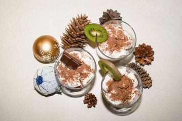 Delicious Christmas dessert on a white background. Dessert with whipped cream and chocolate. Top view. Christmas cones and Christmas balls on the background.