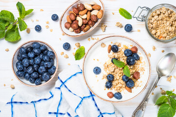 Yogurt granola with fresh blueberries on white wooden table. Top view with copy space. Healthy food, snack or breakfast.