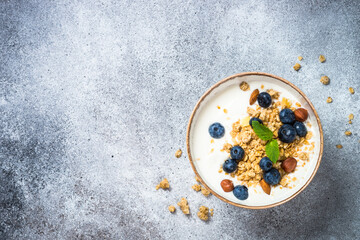 Yogurt with granola and fresh berries at stone table. Top view with copy space.