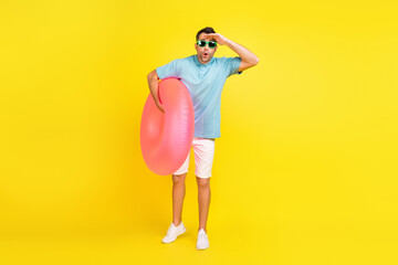 Full length photo of impressed brunet man with circle wear t-shirt eyewear shorts isolated on yellow color background