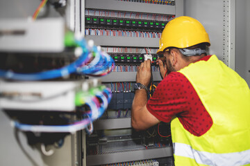 Electrician engineer work tester measuring voltage and current of power electric line in electical cabinet control.