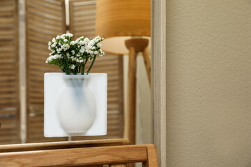 Silicone vase with beautiful white flowers on mirror in room, space for text
