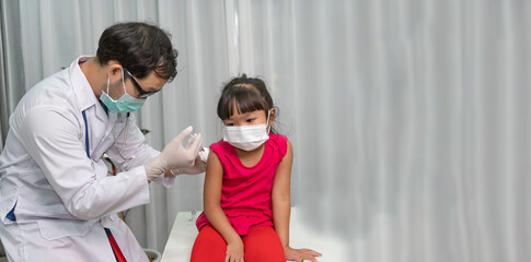 Fototapeta premium Asian doctor injection vaccine for protecting virus covid-19 to a girl wear medical mask,People are Girls are vaccinated against influenza every year.
