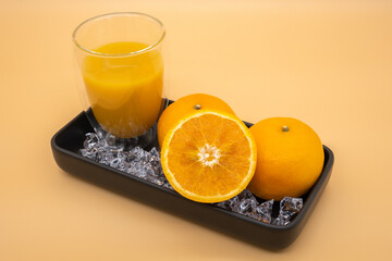 Fresh oranges in black ceramic plate with orange background.