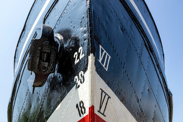 metric and imperial draft marks on the bow of an old ship with reveted hull