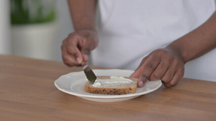 Obraz na płótnie Canvas Close up of African Man Spreading Butter on Bread