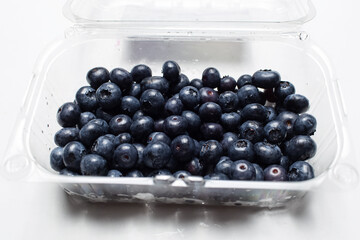 Studio picture of plastic box with fresh blueberries, isolated on white.