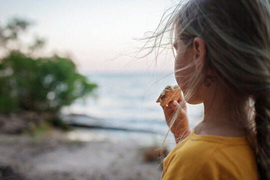 Cute girl roasting marshmallow to make smores over fire flame during camping, traditional American food, active recreation and family travel - Powered by Adobe