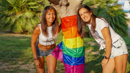 chicas lesbianas con la bandera del movimiento LGBT o LGTB en un parque publico