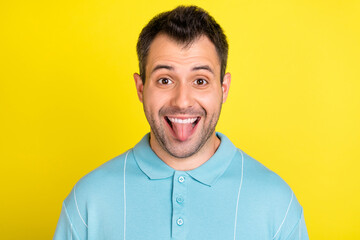 Photo of cool brunet man tongue out wear blue t-shirt isolated on yellow color background