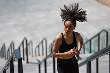 African amerian woman with afro hair running on stairs outdoors