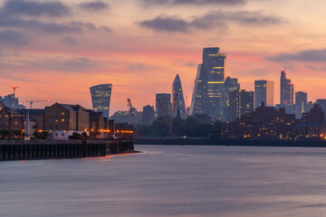 View of The City skyline at sunset from the Thames Path, London, England