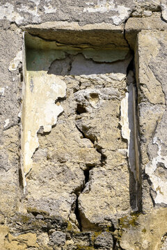 Big crack on gray wall of old dilapidated building, abstract image of vertical crack, detail. Rectangular niche in wall.Consequences of earthquake. Copy space. Selective focus.