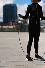 Cropped view of african american sportswoman holding jump rope on urban street