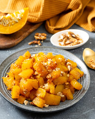 Traditional Turkish dish of baked pumpkin with sugar and walnuts Kabak tatlisi in a blue plate on a culinary background. Delicious healthy dessert closeup