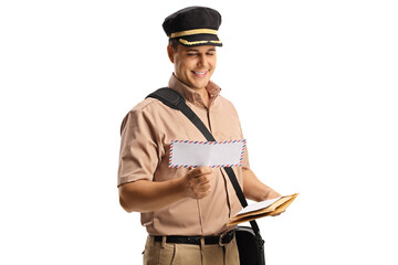 Smiling mailman in a uniform looking at a letter - obrazy, fototapety, plakaty