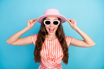 Photo of cheerful tourist lady omg reaction open mouth wear sunglass hat striped dress isolated blue color background