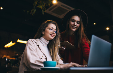 Smiling students correcting project on laptop in restaurant