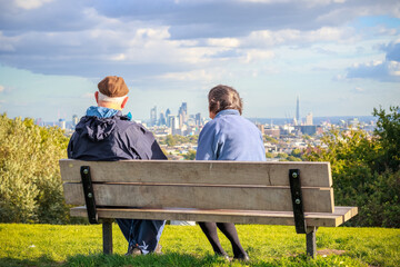 Back view of unidentified senior couple looking over London city skyline from Parliament Hill in Hampstead Heath - obrazy, fototapety, plakaty
