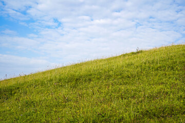 Obraz na płótnie Canvas green hill and blue sky with clouds