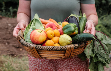 Woman holding a basket full of organic vegetables and fruit
