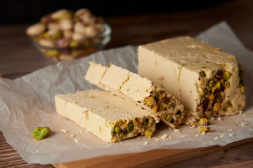 Organic halva with pistachios on a wooden surface. Traditional middle eastern sweets. Jewish, turkish, arabic oriental national dessert. Turkish delight concept. Natural vegan product. Copy space.