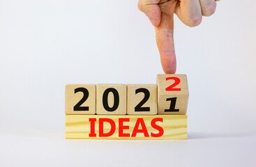 Business concept of planning 2022 ideas symbol. Businesman turns a wooden cube and changes words 'Ideas 2021' to 'Ideas 2022'. Beautiful white background, copy space. Business and ideas 2022 concept.
