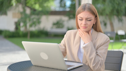 Businesswoman with Laptop Coughing in Outdoor Cafe