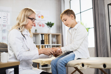 Obraz premium Teenage boy having medical consultation with competent doctor at modern clinic. Female physician examining male patient at own cabinet. Concept of health care.