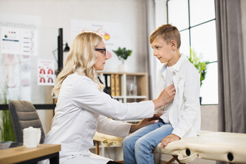 Professional high-skilled female pediatrician examining heartbeat and lungs breathing of 12-aged...