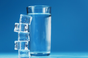 A glass of ice and clear water, ice cubes on a blue background.