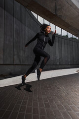 Fototapeta na wymiar African american runner training near building on urban street
