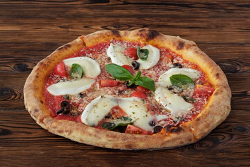 Oven baked pizza with buffalo mozzarella, parmigiano-reggiano cheese, basil and anchovies. Traditional italian dish on white wood textured table background. Close up, copy space, top view.