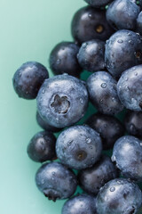 A lot of beautiful juicy fresh summer blueberries on a light turquoise glass plate