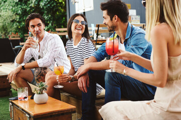 Group of young people drinking cocktails at a summer bar during the day