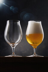 Two beer glasses. Glass full of light yellow beer and empty glass on a dark background. Selective focus