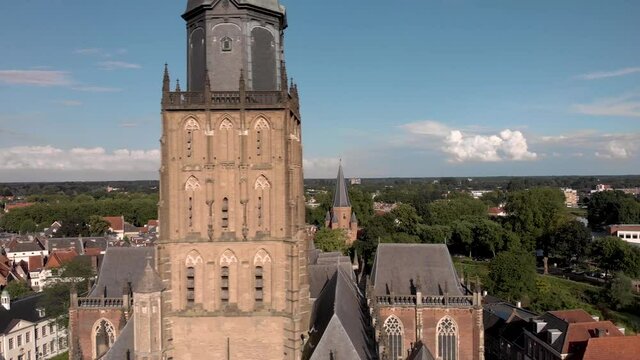 Closeup of Walburgiskerk cathedral tower revealing church ship and Drogenapstoren medieval city wall entrance tower in the background. Dutch cultural heritage historic architecture.