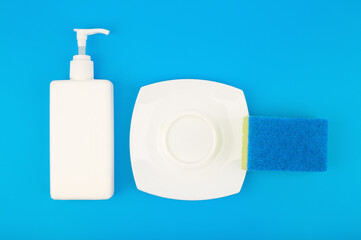 Creative dishwashing concept, top view of detergent, cleaning sponge and clean plate isolated on blue background