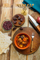 Jewish dish cholent with meat ingredients and menorah on the table.