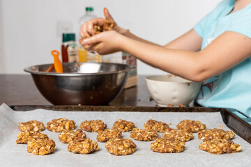 Obraz na płótnie Canvas Liittle girl hands preparing oatmeal chocolate chips cookies